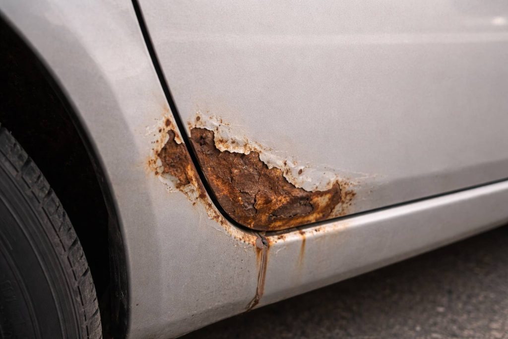 Rust on car door panel needing car painting and repair.