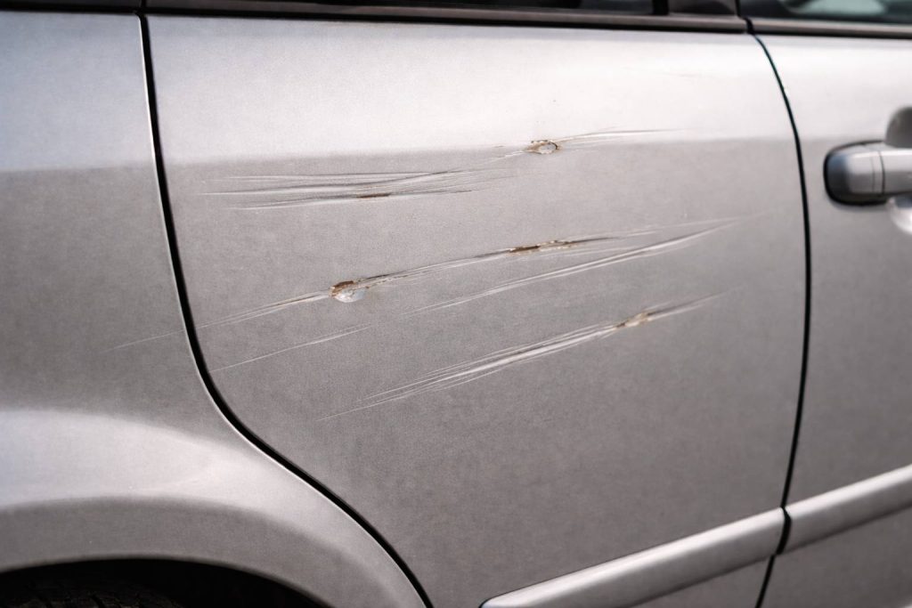 Car painting repair needed for scratched and chipped car surface.